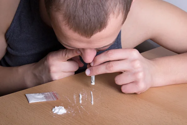 Verslaafd man snuiven heroïne uit de tabel — Stockfoto
