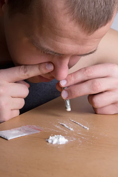 Addict snorting heroin with dollar from the table — Stock Photo, Image