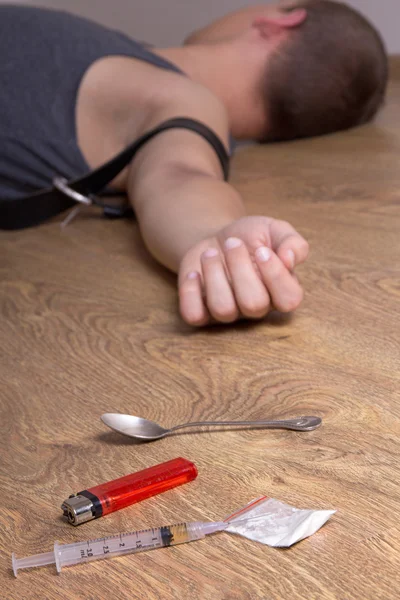 Spoon, accendino, siringa con la droga e tossicodipendente sdraiato sul pavimento — Foto Stock