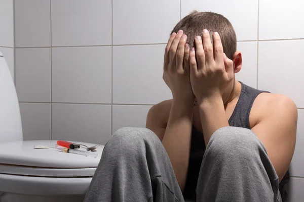 Gestenigd man met heroïneverslaving zitten in badkamer Stockfoto