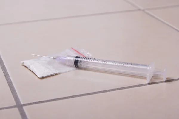 Drug syringe and heroin powder on the floor — Stock Photo, Image