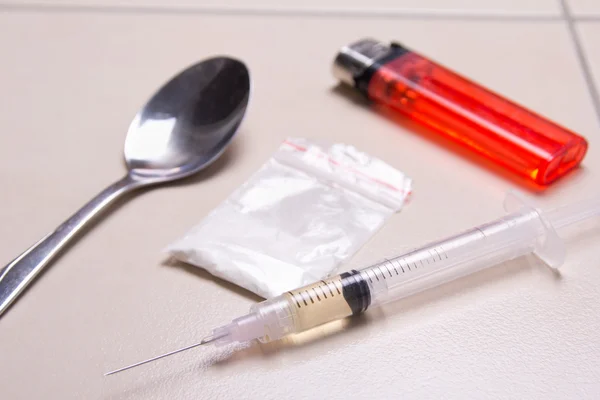 Close up of drug syringe, heroin powder, spoon and lighter on th — Stock Photo, Image