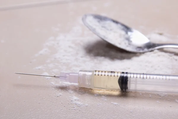 Spritze mit Arzneisubstanz, Heroin-Pulver und Löffel auf die floo — Photo