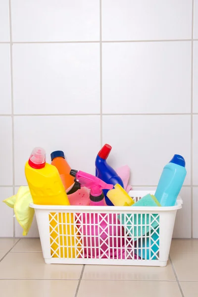 Cleaning supplies in plastic basket on tiled floor — Stock Photo, Image