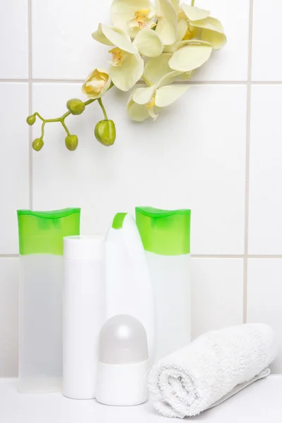 Set di flaconi per la cosmetica bianche con orchidea gialla sul muro piastrellato — Foto Stock