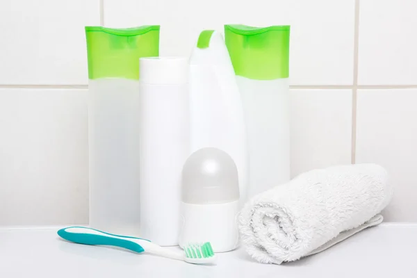 Satz von weißen Kosmetik-Flaschen mit Handtuch und Zahnbürste über til — Stockfoto