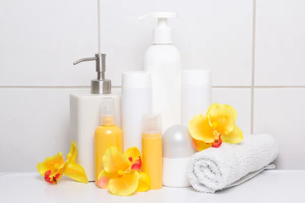 collection of cosmetic bottles with orange flowers over white ti