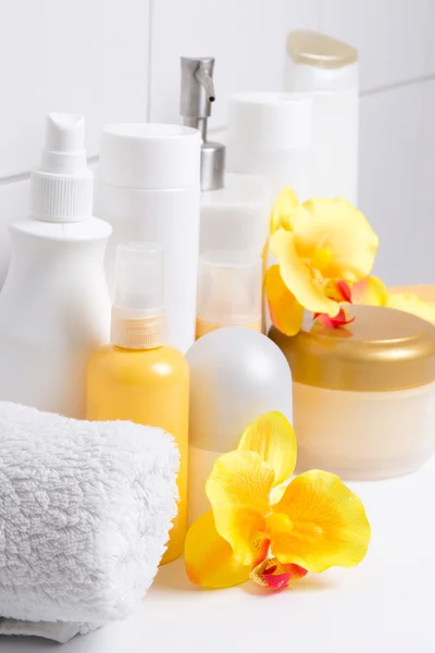 Set of white cosmetic bottles with flowers over tiled wall – stockfoto