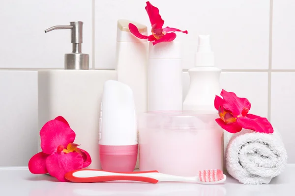 Sada bílých kosmetických lahví, ručník a zubní kartáček s červeným flo — Stock fotografie