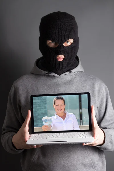 Человек в маске с компьютером с изображением женщины, давая деньги — стоковое фото