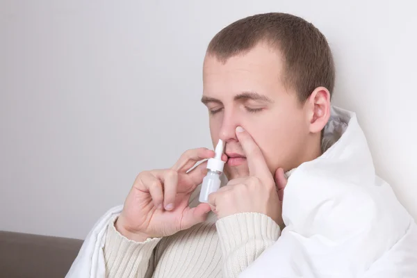 Człowiek przy użyciu spray do nosa w jego salonie — Zdjęcie stockowe