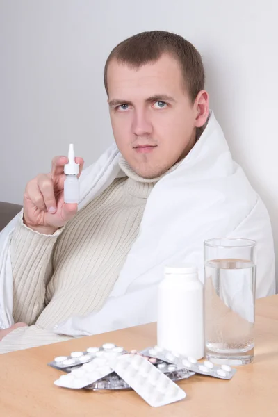 Hombre enfermo mostrando el aerosol nasal en sala de estar — Foto de Stock