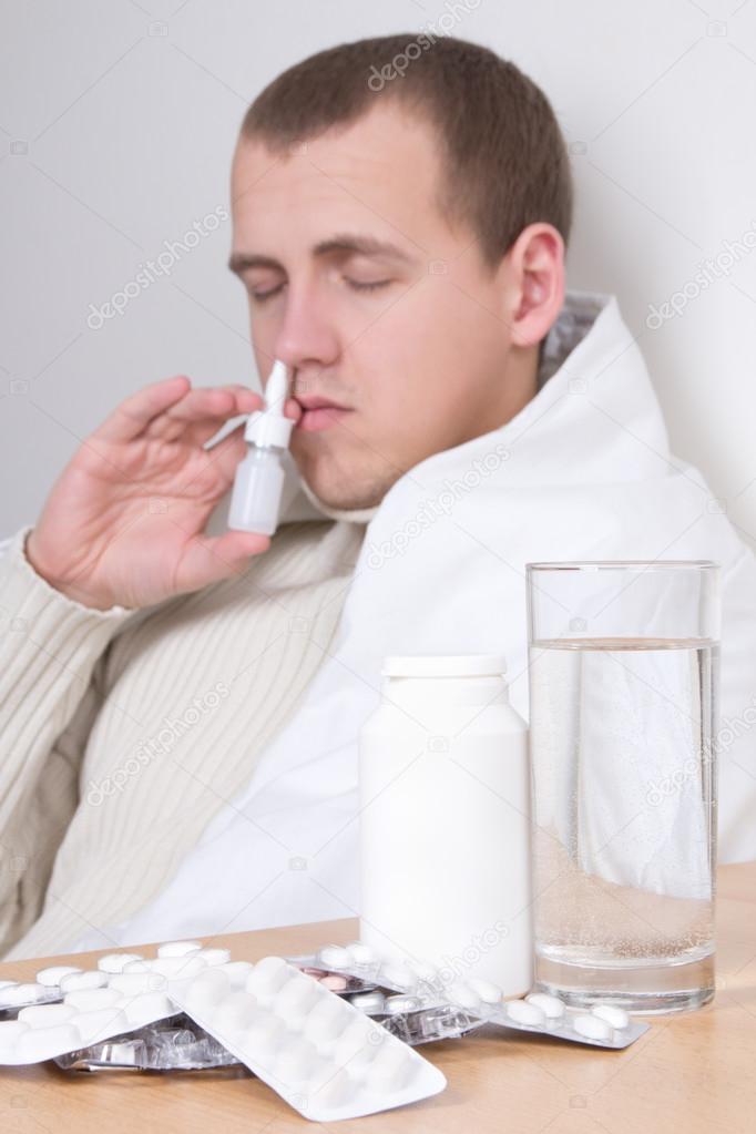 sick man using nasal spray in living room