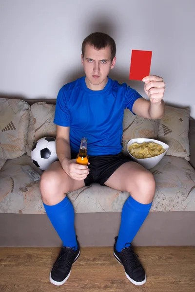 Viendo fútbol en la televisión en casa y mostrando rojo tarjeta joven —  Fotos de Stock