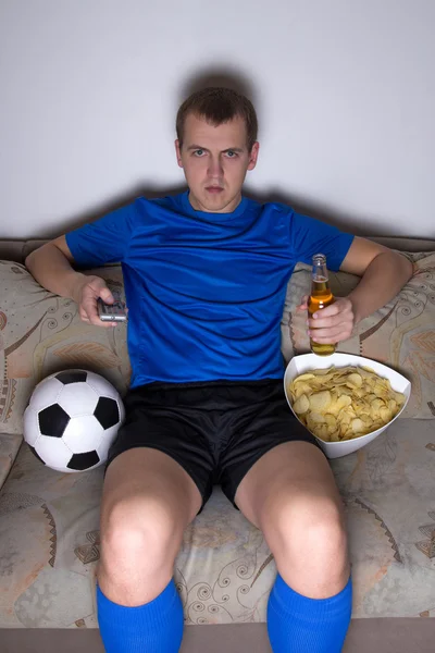 Uomo annoiato in uniforme seduti in salotto e guardare calcio — Foto Stock