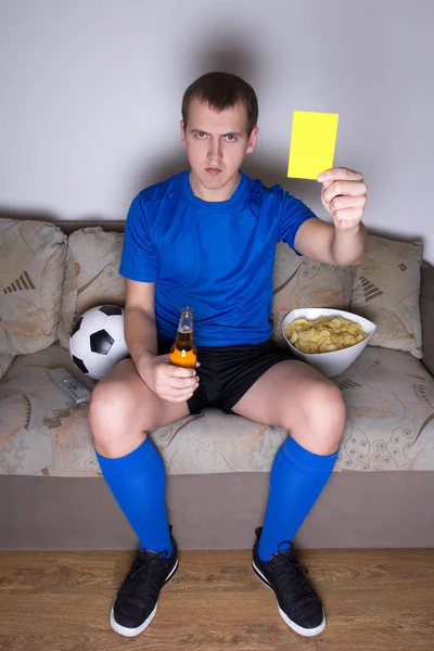 Young man watching football on tv at home and showing yellow car — Stock Photo, Image