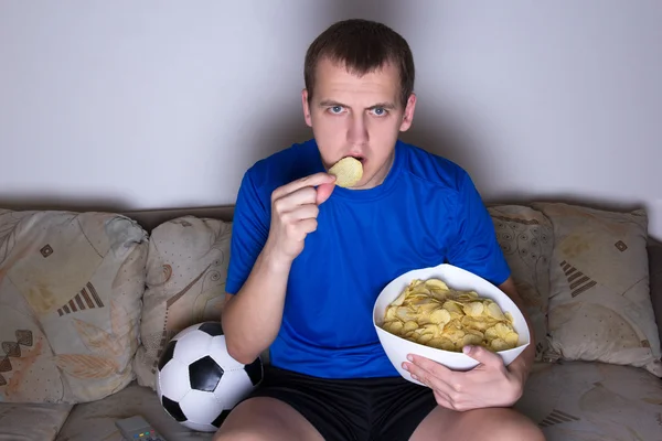 Sostenitore in uniforme di guardare il calcio in tv a casa e mangiare — Foto Stock