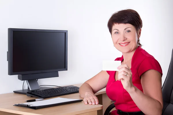 Middle aged businesswoman with visiting card sitting in office — Stock Photo, Image