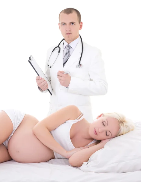 Jovem médico bonitão e a mulher grávida deitada na cama o isolado — Fotografia de Stock
