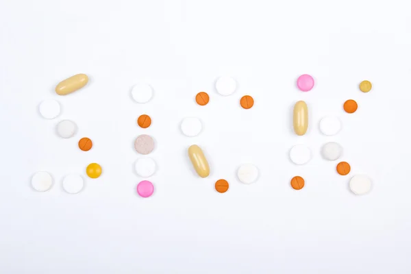 Sick word text made of colorful tablets, pills and capsules — Stock Photo, Image