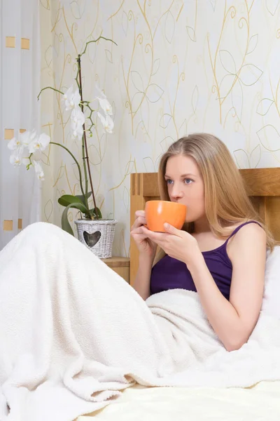 Mooie vrouw koffie of thee drinken in slaapkamer — Stockfoto