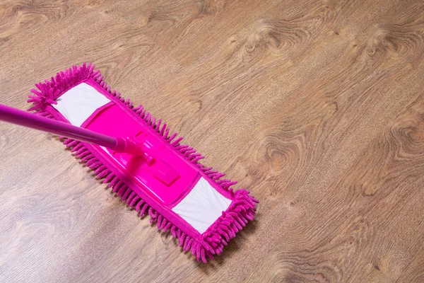 用粉红色的拖把清洗的镶木地板 — 图库照片