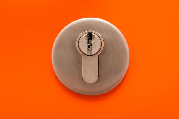 Close up of keyhole on orange door — Stock Photo, Image