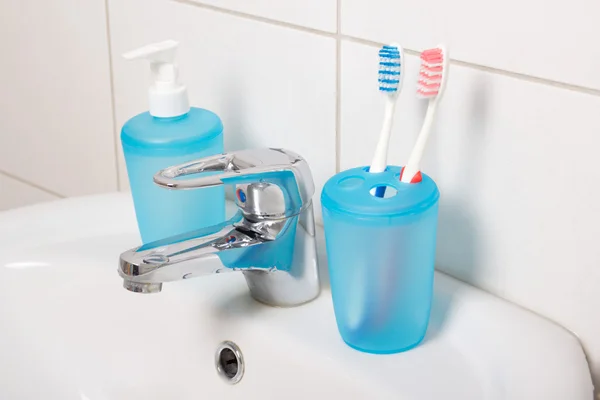 Tooth brushes and soap on white sink — Stock Photo, Image