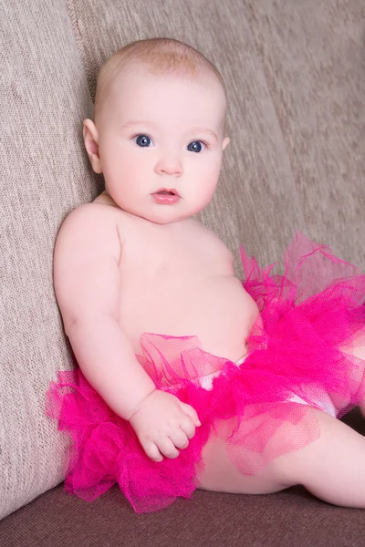 Funny baby girl in pink skirt sitting — Stock Photo, Image