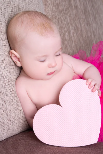 Funny baby girl in pink skirt with heart sitting — Stock Photo, Image