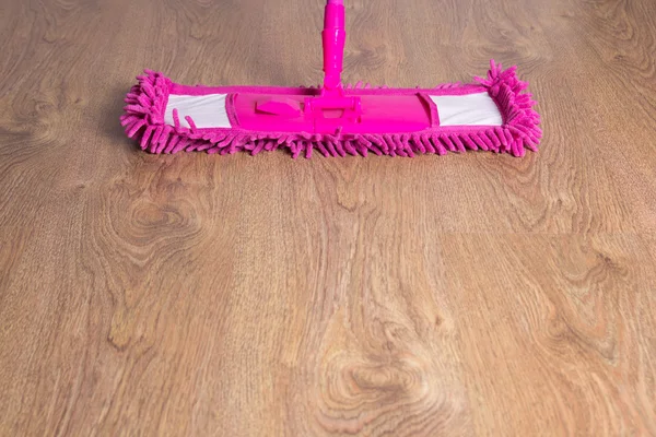 Close up of wooden floor with pink mop — Stock Photo, Image
