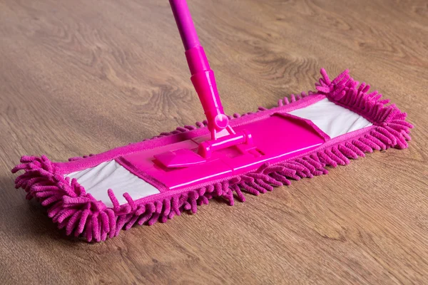 Foto de piso de madera de cerca con trapeador rosa —  Fotos de Stock