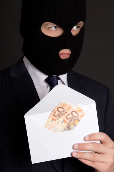 Concepto de soborno - hombre enmascarado en traje sosteniendo envolvente con dinero — Foto de Stock