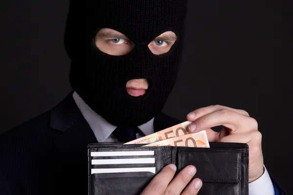Корупційна концепція чоловік у діловому костюмі та масці, що тримає шкіру — стокове фото