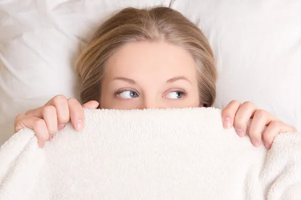 Retrato de mujer joven divertida tumbado en la cama bajo la manta —  Fotos de Stock