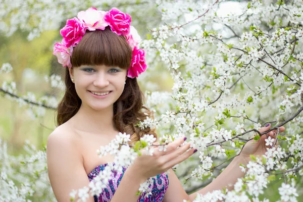 Meisje met bloemen op kop en bloeiende boom Rechtenvrije Stockfoto's