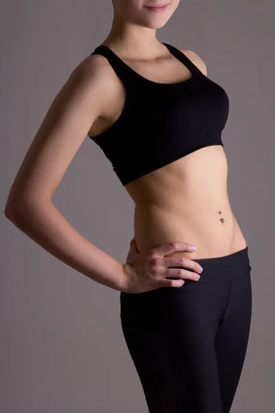 Sottile corpo di donna in abbigliamento sportivo sopra grigio — Foto Stock