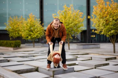Aile ve mutluluk kavramı - neşeli baba ve küçük kızı sonbahar parkında yürüyor ve eğleniyorlar.