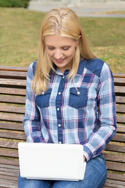 十几岁的女孩坐在长凳上公园与笔记本电脑 — 图库照片