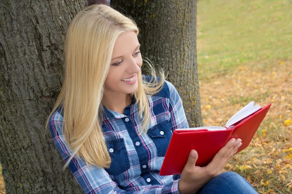 Linda mulher feliz sentado no parque e lendo o livro — Fotografia de Stock