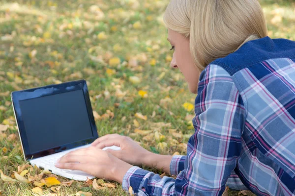 Belle femme utilisant un ordinateur portable avec écran vide dans le parc d'automne — Photo