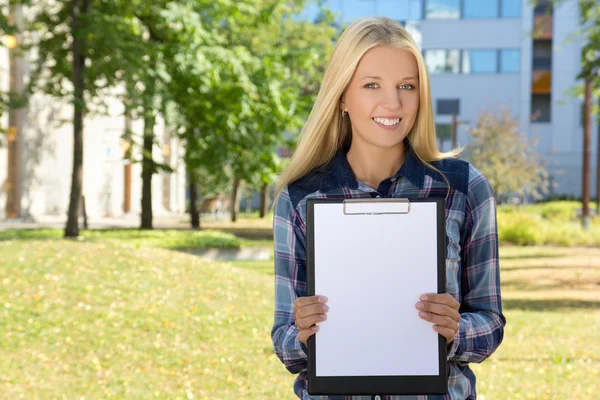Beautiful woman showing clipboard with copyspace in autumn park — ストック写真