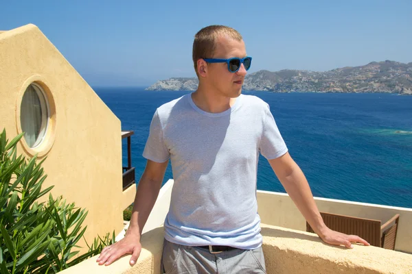 Young man standing on balcony with sea view — Stock Photo, Image