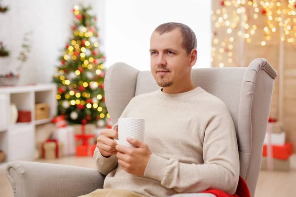 Ung Man Med Kopp Kaffe Sittandes Fåtölj Juldekorerat Rum — Stockfoto