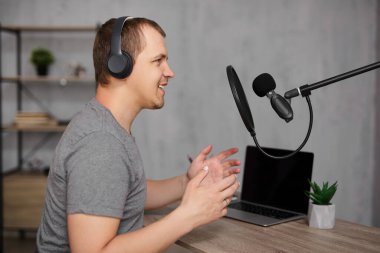 yaratıcılık, medya içeriği, podcast ve blog konsepti - mikrofon ve kulaklıklı bir adam ev ofisinde veya stüdyoda podcast kaydediyor