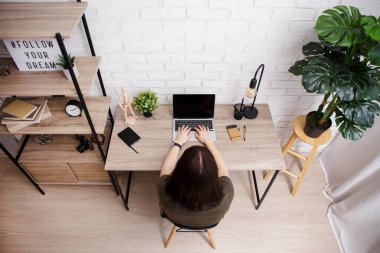 Evdeki dizüstü bilgisayarda bir şey yazan kadının üst görünümü