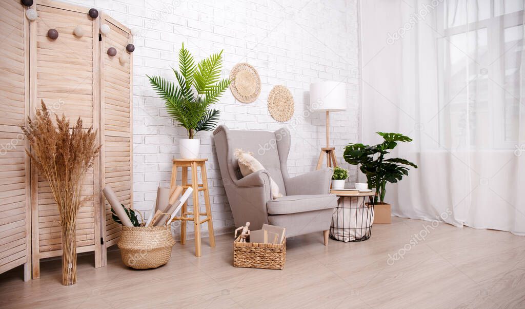Scandinavian room with armchair, lamp, plants and window over brick wall