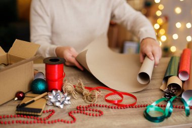 Evde Noel hediyelerini paketleyen adamın ellerini kapat.