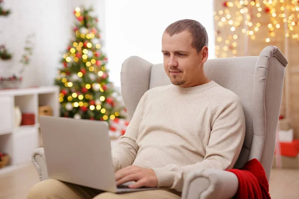 Glücklicher Mann Sitzt Auf Sessel Mit Laptop Weihnachtlich Dekorierten Zimmer — Stockfoto
