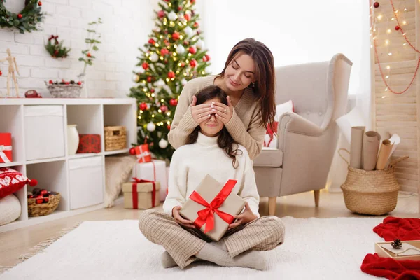크리스마스 놀라움의 엄마가 크리스마스 트리로 장식된 거실에서 딸에게 크리스마스 선물을 — 스톡 사진
